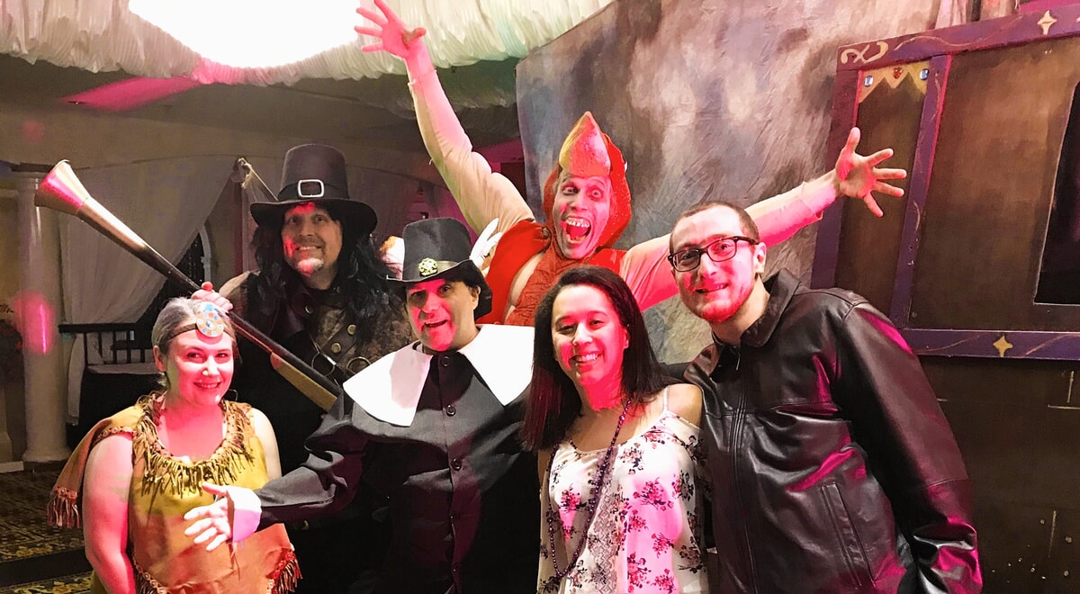 The cast of "The Mayflower Murder" gathered around a Thanksgiving table, striking comedic and suspicious poses for this November murder mystery show.